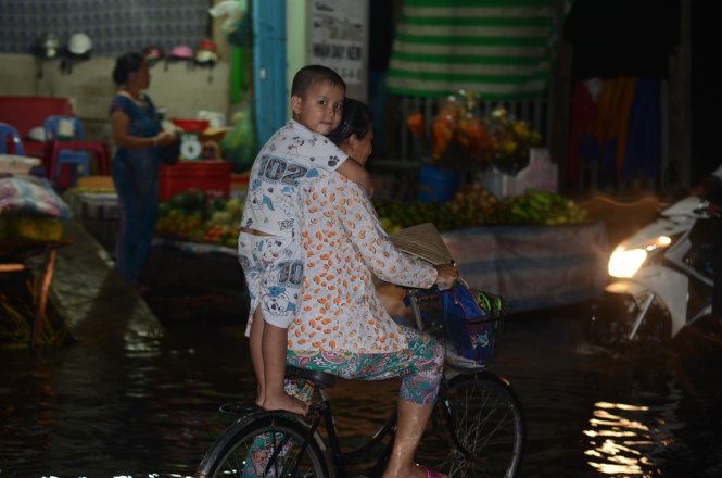 Một đứa trẻ đứng lên xe tránh đường ngập trên đường Kinh Dương Vương, P. An Lạc, Q. Bình Tân - Ảnh: T.Tùng