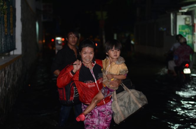 Chị Quang Thị Bé cùng bé Bảo Ngọc vừa vượt quảng đường hơn 300km từ Cà Mau lên Sài Gòn, lại gặp phải cảnh đường ngập - Ảnh: T.Tùng