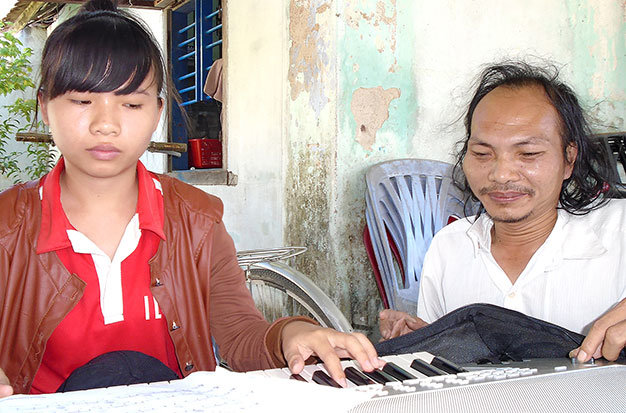 Thầy Nguyễn Tư dạy đàn cho một học sinh - Ảnh: Bích Nhàn