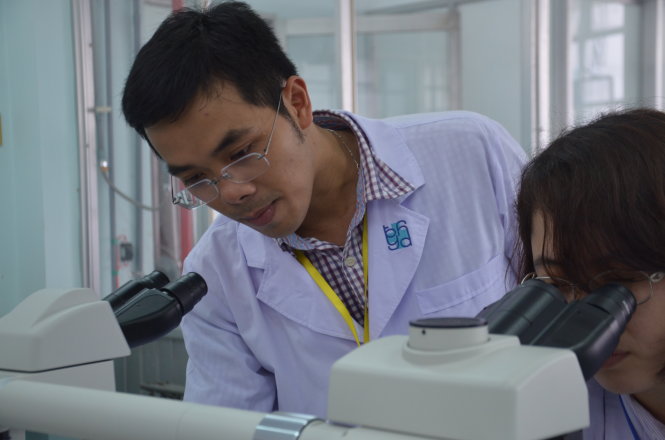 Bác sĩ Nguyễn Lê Việt Hùng cùng đồng nghiệp thực hiện soi vi phẫu (tế bào động vật) bằng kính hiển vi - Ảnh: Mỹ Duyên