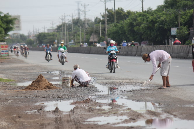 Một người dân sống bên quốc lộ 1, đoạn qua xã Mỹ Yên, huyện Bến Lức (Long An) tự sửa chữa mặt đường đoạn trước nhà ông - Ảnh: Mậu TRường