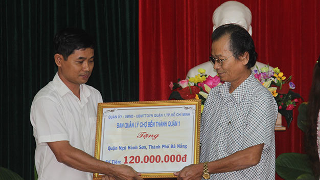 Ban quản lý Chợ Bến Thành, Quận 1, TP HCM (bên trái) trao số tiền ủng hộ xây nhà cho hộ chính sách quận Ngũ Hành Sơn (TP Đà Nẵng) - Ảnh: Trường Trung.