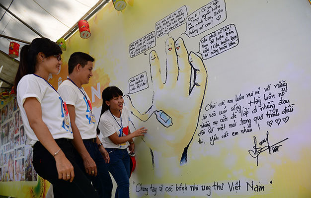 Các bạn trẻ xem dãy tường triển lãm có hình bàn tay của bạn A Pảo Tòng gửi đến chương trình được trưng bày tại ngày hội Hoa hướng dương sáng 2-11 ở TP.HCM - Ảnh: Quang Định