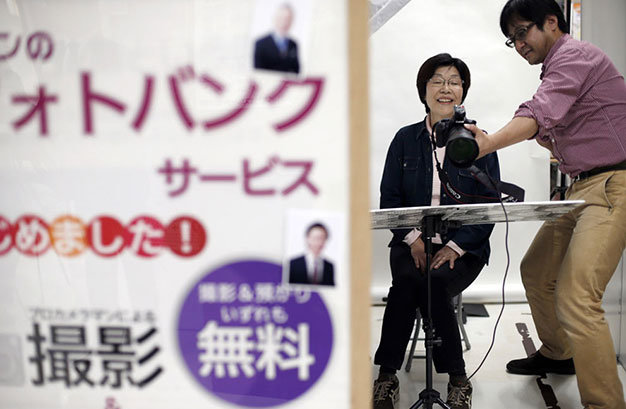 Một phụ nữ mỉm cười khi chụp ảnh thờ trong buổi hội thảo về dịch vụ tự lo hậu sự ở Tokyo - Ảnh: Reuters
