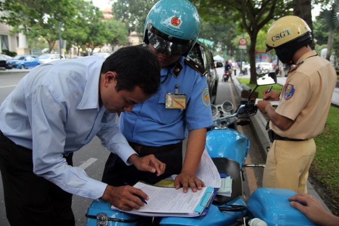 Một tài xế taxi Uber ký vào biên bản vi phạm hành chính trên đường Lê Duẩn (Q.1) - Ảnh: M.Trường