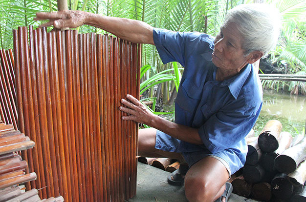 Dù đã 77 tuổi nhưng ông Lê Công Thành vẫn rất điệu nghệ trong nghề làm nhà lá của Cẩm Thanh, Hội An - Ảnh: Đoàn Cường