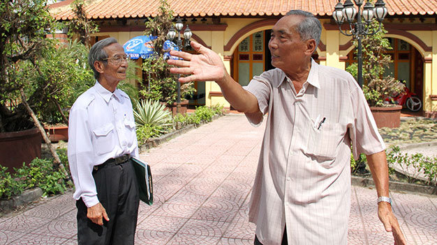 Ông Bé “rẫy” (phải) và ông Võ Hưng Thông kể chuyện lực lượng vũ trang tập luyện trước chùa Ông chuẩn bị cho Cách mạng Tháng Tám và toàn quốc kháng chiến - Ảnh: V.Tr.