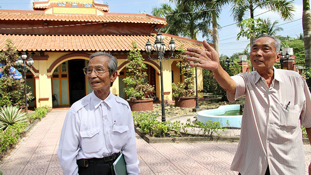 Ông Bé “rẫy” (phải) và ông Võ Hưng Thông kể chuyện lực lượng vũ trang tập luyện trước chùa Ông chuẩn bị cho Cách mạng Tháng Tám và toàn quốc kháng chiến - Ảnh: V.Tr.