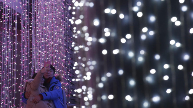 Còn tại thủ đô Bắc Kinh, Trung Quốc, một cặp đôi tranh thủ chụp ảnh làm kỷ niệm trong lúc dạo phố đêm Giáng sinh - Ảnh: Reuters