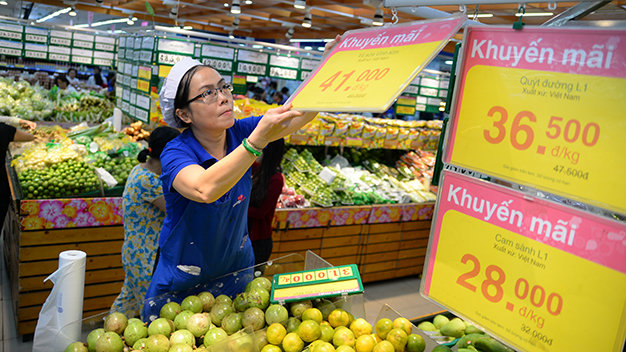 Nhân viên siêu thị Co.op Mart Đinh Tiên Hoàng (Q.Bình Thạnh, TP.HCM) treo bảng giảm giá đối với các loại trái cây vào sáng 25-12 - Ảnh: Hữu Khoa