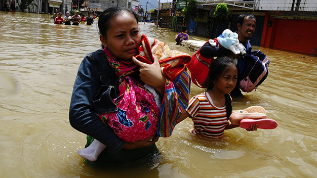 Người dân ôm đồ lội nước lụt  đi sơ tán ở Tây Java, Indonesia - Ảnh: Reuters