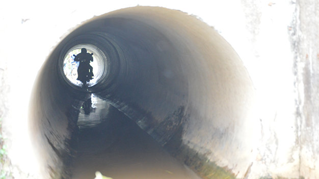 Một người dân chạy xe máy trong đường ống cống - Ảnh: N.Tài