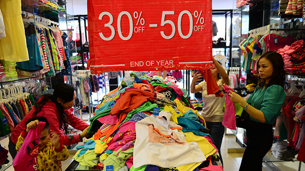 Mua quần áo giảm giá tại một cửa hàng trên đường Hai Bà Trưng, Q.1, TP.HCM để bảng giảm giá từ 30-50% - Ảnh: Quang Định