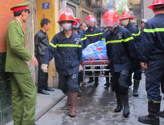 Lực lượng chữa cháy đưa thi thể nạn nhân ra ngoài - Ảnh: Thân Hoàng