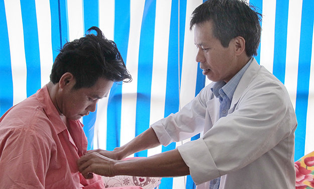 TS. BS Vũ Hữu Vĩnh đang thăm khám vết thương cho bệnh nhân - Ảnh: Thùy Dương