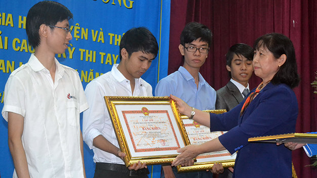 Bà Nguyễn Thị Liên, phó giám đốc Sở LĐ-TB&XH TP.HCM, trao bằng khen của chủ tịch UBND TP.HCM cho các học sinh, sinh viên - Ảnh: Q.Phương