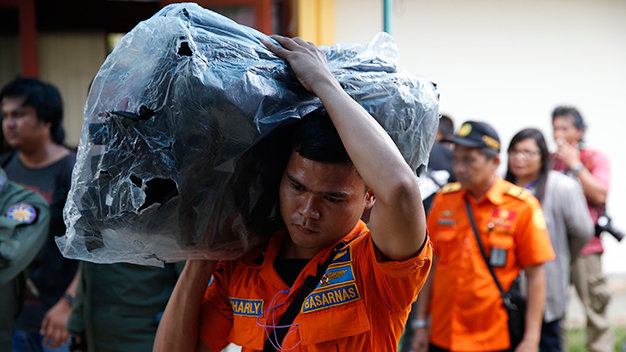 Một thành viên đội cứu hộ chuyển túi lên máy bay để đựng các thi thể vớt ngoài biển - Ảnh: Reuters