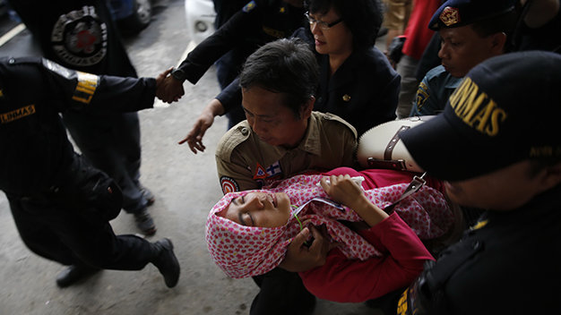 Nhân viên an ninh đưa một thân nhân của hành khách bị ngất xỉu sau khi nghe tin xấu - Ảnh: AFP