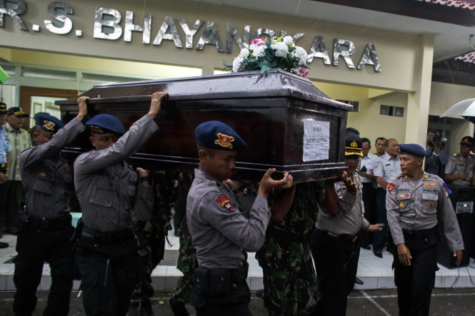 Cảnh sát Indonesia khiêng quan tài chứa thi thể một hành khách ở bệnh viện tại thành phố Surabaya - Ảnh: Reuters