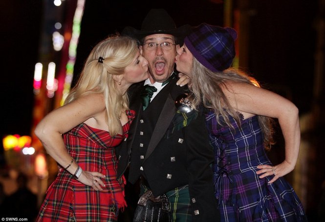 Anh Thomas Haworth bất ngờ hạnh phúc khi được 2 cô bạn Kasey Snyder và Heather Haworth hôn trong lúc diễn ra lễ tất niên ở thủ đô Edinburgh, Scotland - Ảnh: Daily Mail