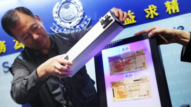 Cảnh sát Hong Kong đang dùng đèn chiếu để phân biệt tiền thật và giả - Ảnh: scmp