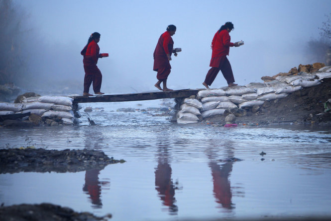 Những người phụ nữ đi qua cầu ván bắt ngang sông Salinadi - Ảnh: AP