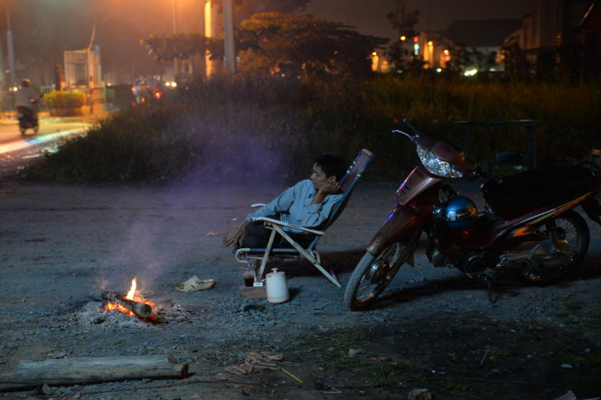 Trong lúc đợi khách, ông Nguyễn Văn Lâm chạy xe ôm trên đường Nguyễn Văn Linh (Q.8, TP.HCM) tranh thủ nhóm lửa chống lạnh