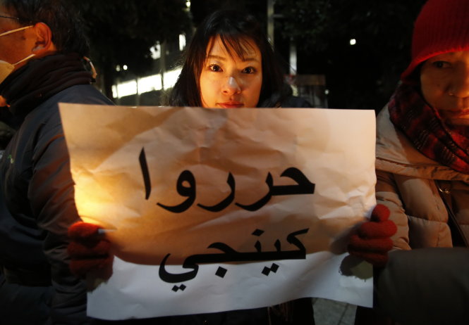 Một người phụ nữ Nhật cầm tờ giấy ghi dòng chữ “Trả tự do cho Kenji” trước dinh thự Thủ tướng Shinzo Abe ở Tokyo - Ảnh: Reuters 