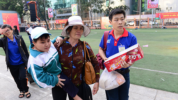 Bà Đặng Thị Thiểu bồng con trai Dương Văn Thành chuẩn bị lên xe về Quảng Trị đón tết trong lễ tiễn  sinh viên về quê ăn tết sáng 10-2 - Ảnh: Quang Định