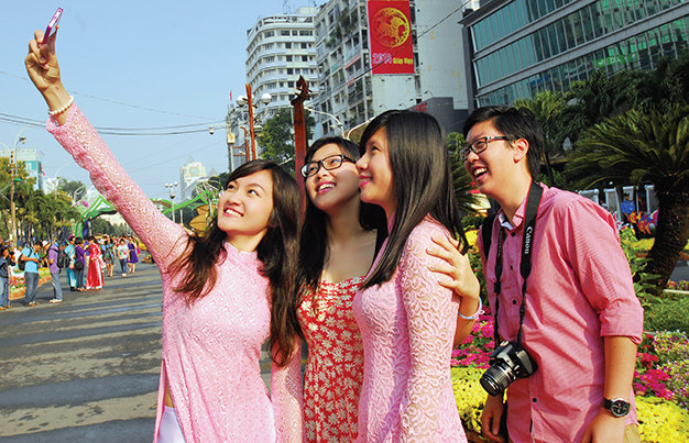 Nhóm bạn trẻ chụp ảnh kỷ niệm bên đường hoa xuân Nguyễn Huệ TP.HCM - Ảnh: Hoàng thạch vân