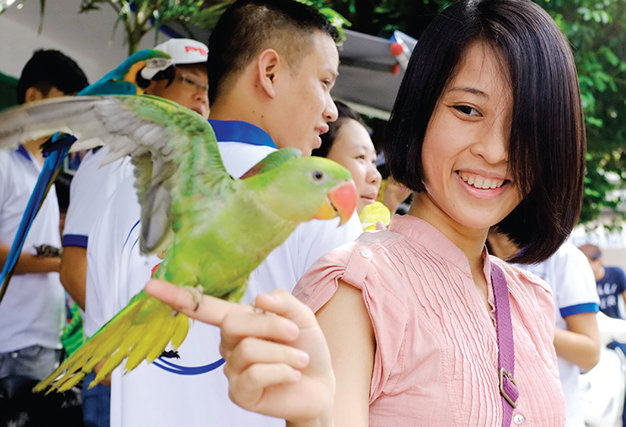 Nụ cười hài lòng của chị Nguyễn Bích Lan khi vui chơi cùng chú vẹt của mình 