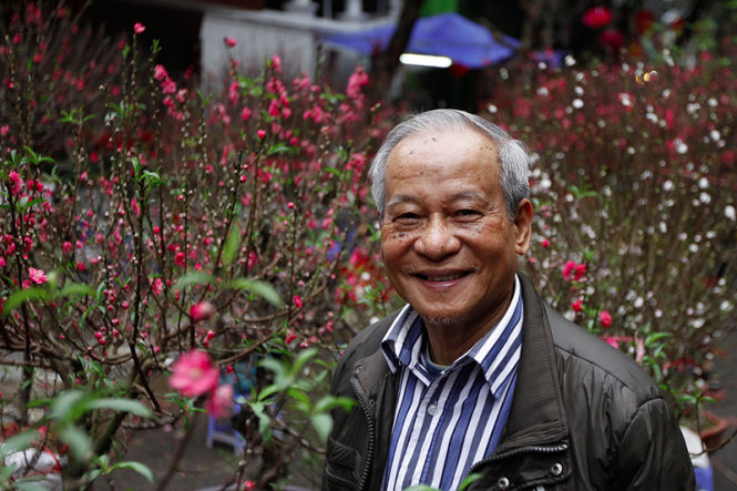 Ông Bùi Thế Năng một người dân sinh ra và lớn lên tại Hà Nội mỉm cười bên cạnh những cành đào xuân - Ảnh: Nguyễn Khánh
