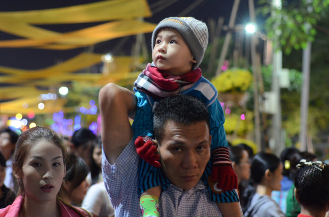 Một đứa bé được đưa lên vai bố đi chơi trên đường hoa Hàm Nghi - Ảnh: Thanh Tùng