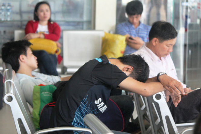Một người dân mệt mỏi ngủ gật chờ xe tại Bến xe Vinh chiều 23-2 - Ảnh: Doãn Hoà