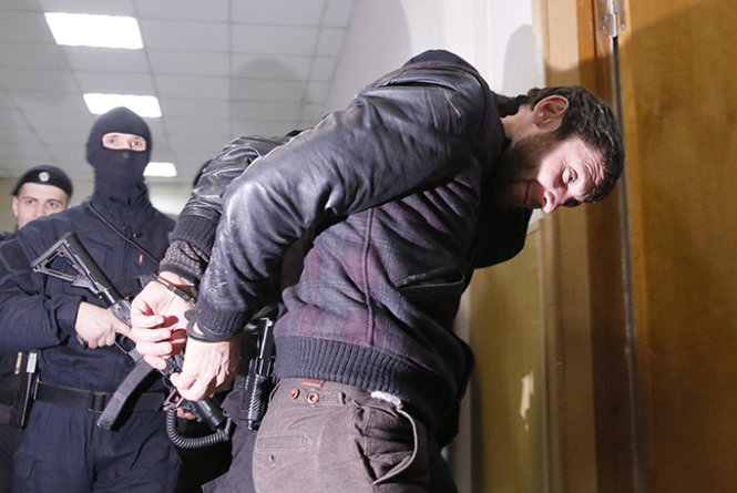 Zaur Dadayev bị cảnh sát dẫn giải trong khu nhà của tòa án ở Matxcơva ngày 8-3 - Ảnh: Reuters