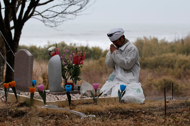Ông Norio Kimura cầu nguyện bên mộ người thân mất do động đất và sóng thần 11-3-2011 - Ảnh: Reuters