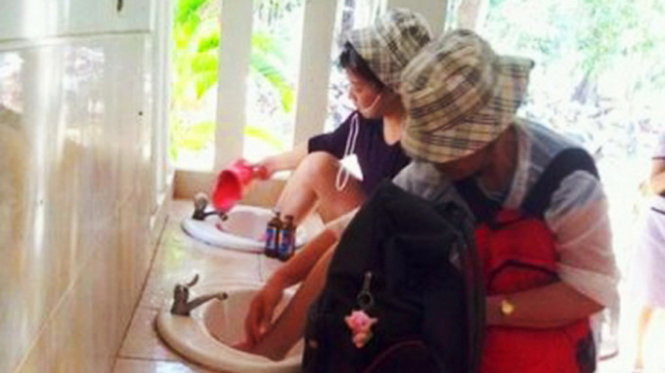 Hai du khách Trung Quốc ngang nhiên rửa chân trên bồn rửa mặt trong nhà vệ sinh công cộng ở Thái Lan - Ảnh: Phuketwan.com