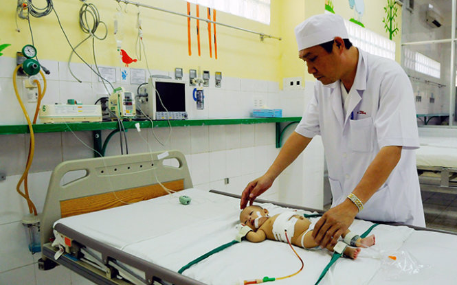 Bác sĩ Vũ Công Tầm, trưởng khoa Phẫu thuật gây mê - Hồi sức, Bệnh viện Nhi đồng Đồng Nai đang chăm sóc cho bé L. sau phẫu thuật - Ảnh: A Lộc