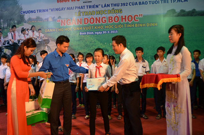 Bí thư Tỉnh Đoàn Bình Định (trái) và đại diện Nutifood Trần Thanh Hải trao học bổng cho học sinh - Ảnh: Tr.Đăng