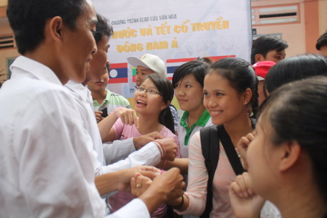 Bạn trẻ hào hứng khi được các sinh viên người Campuchia buộc chỉ cổ tay, kèm theo lời chúc tết của họ - Ảnh: Khoa Nguyễn