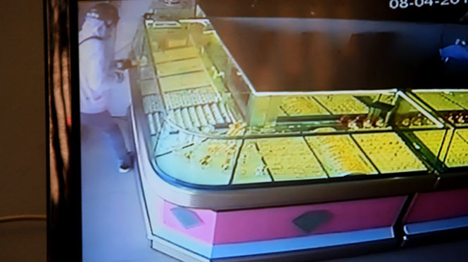 Đối tượng cướp đang dùng tay lấy vàng trong tủ kính - Ảnh cắt từ camera của tiệm vàng