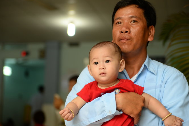 Hai cha con bé Huy có mặt tại bệnh viện Nhi Đồng 1, TP.HCM để kiểm tra sức khỏe và học vật lý trị liệu - Ảnh: Hữu Khoa