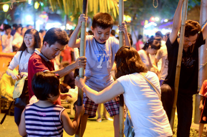 Một đứa trẻ được hướng dẫn đi cà kheo tại lễ hội -Ảnh: Tùng Tin