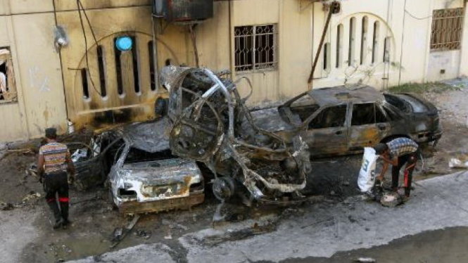 Người dân Iraq bên cạnh những chiếc ôtô cháy nát trong vụ bom xe ngày 1-5 ở khu vực Talbiya, gần thủ đô Baghdad - Ảnh: AFP