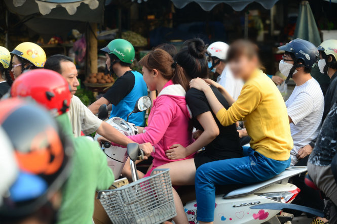 Ba phụ nữ chạy xe máy không đội nón bảo hiểm chở 3 trên đường Vũ Tùng, Q. Bình Thạnh, TP.HCM  - Ảnh: Tiến Long
