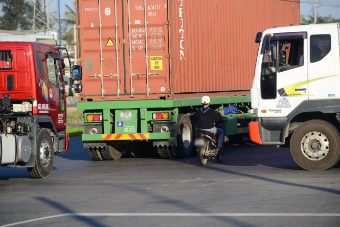 Một chiếc xe máy cố gắng len vào ngỏ hẹp giữa các xe container tại vòng xoay Mỹ Thủy, TP.HCM - Ảnh: Tiến Long