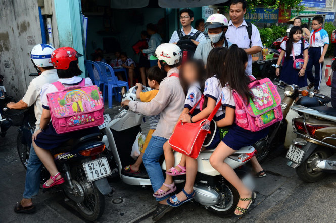 Một phụ huynh chở thêm 4 trẻ nhưng không được đội nón bảo hiểm tại Trường Tiểu học Hàm Tử, Q.5, TP.HCM  - Ảnh: Tiến Long