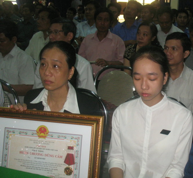 Người thân của ông Lê Minh Phú đón nhận Huân chương dũng cảm thay ông - Ảnh: Bích Quân
