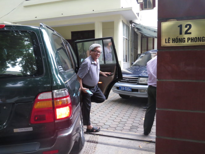 Ông Kim Quốc Hoa được dẫn ra ôtô đưa đến trụ sở thực hiện lệnh khám xét - Ảnh: Minh Quang