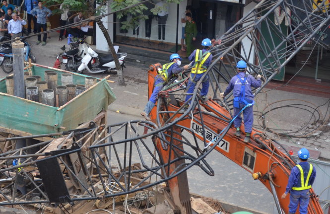 Công nhân cắt đôi cần cẩu và cẩu khỏi nhà dân khoảng 18g ngày 12-5 - Ảnh: Tuấn Phùng